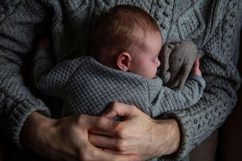 Father holding an asleep baby in his arms